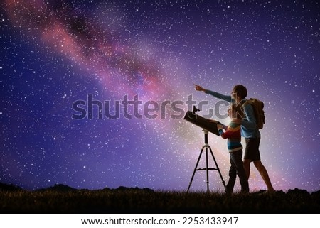 Man and child looking at stars through telescope. Family camping and hiking fun. Outdoor astronomy hobby. Parent and kid watch night sky with milky way. Boy observing planets and moon.  Royalty-Free Stock Photo #2253433947