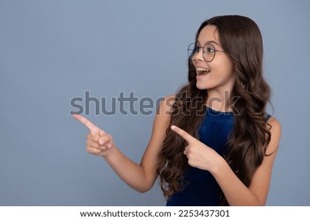 Wow, it's unbelievable. Shocked teenager child pointing aside at copy space. Teen girl pointing with two hands and fingers to the side. Happy girl face, positive and smiling emotions.