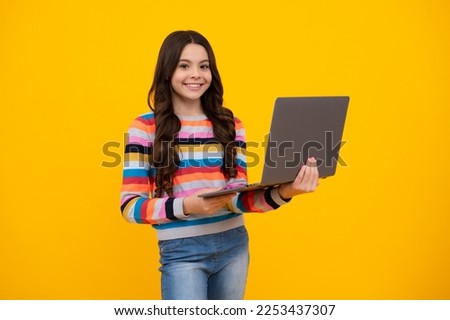 School student using laptop. E-learning and online education. Teen girl on internet video chat isolated on isoalted yellow background. Happy teenager, positive and smiling emotions of teen schoolgirl.
