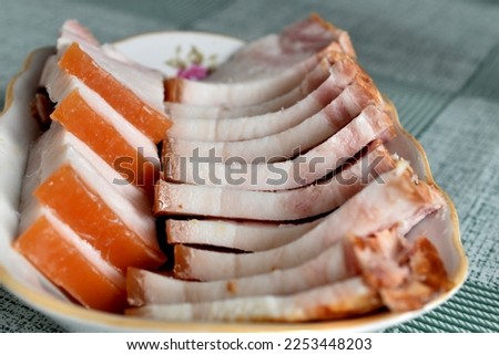 In the picture, slices of chopped lard lie in rows on a plate.