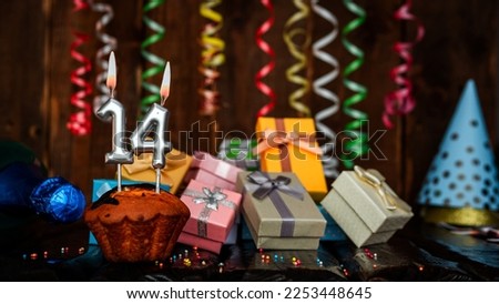 Birthday background with muffin and candles with number  14. Beautiful anniversary background with cake copy space with burning candles. Gift boxes with decorations.