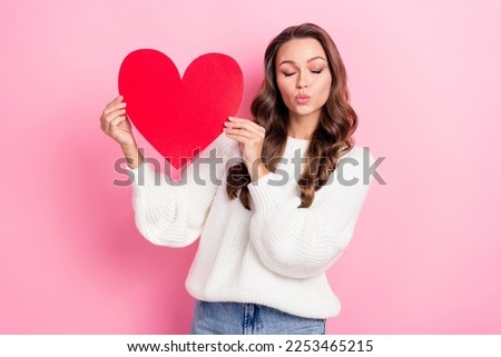 Photo of lovely cute girl closed eyes pouted lips kiss hold red paper heart isolated on pink color background
