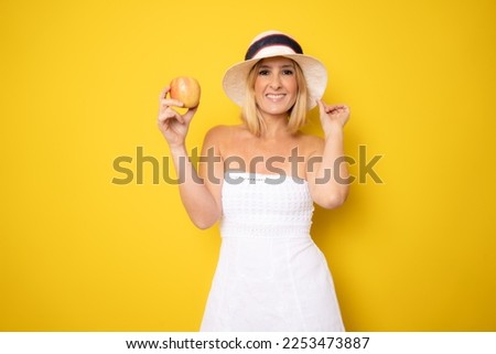smiling woman with healthy teeth holding red apple isolated over yellow background.