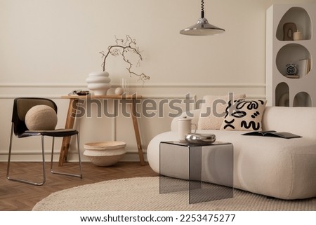 Interior design of living room interior with white modular sofa, chrom bowl, lamp, glass coffee table, wooden bench, stylish rack, beige wall with stucco and personal accessories. Home decor. Template Royalty-Free Stock Photo #2253475277