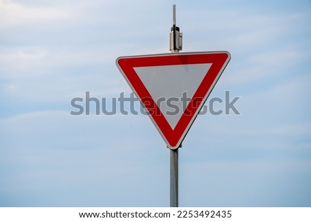 A blank triangle warning road sign against the blue sky
