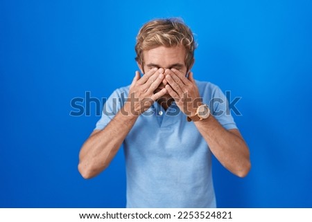 Caucasian man standing over blue background rubbing eyes for fatigue and headache, sleepy and tired expression. vision problem 