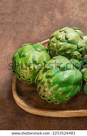 Artichoke flower buds. Fresh and raw artichoke on the wooden table. Copyspace. Top view
