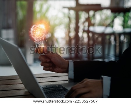 Inspiration and creative management concepts. Many gears working inside creative idea light bulb holding by businessperson hand who working with laptop computer. Business solution for successful. Royalty-Free Stock Photo #2253527507