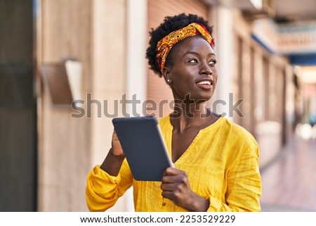 Young african american woman smiling confident using touchpad at street Royalty-Free Stock Photo #2253529229