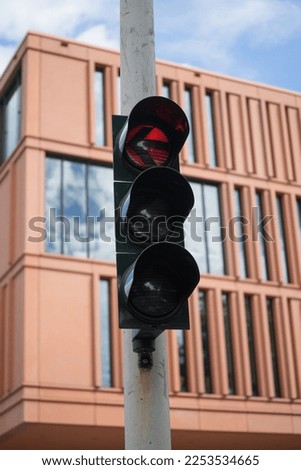 A closeup shot of a traffic light showing a red light for cars turning left the street on a sunny day