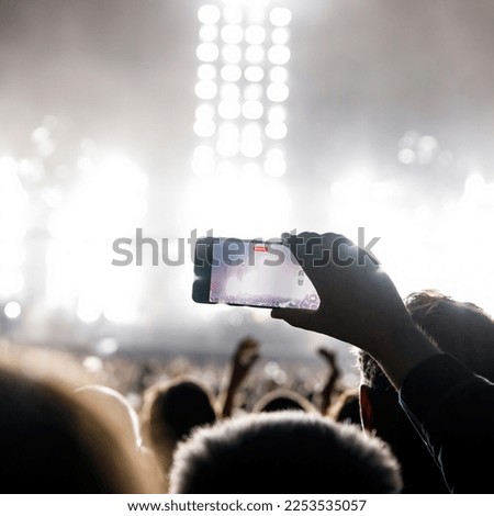 Making video of concert using a smartphone. Cheering people on an amazing music show