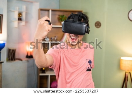 sweet excited young man with VR or virtual reality goggles doing workout by using joystick at home - concept of metaverse, health care and technology. Royalty-Free Stock Photo #2253537207