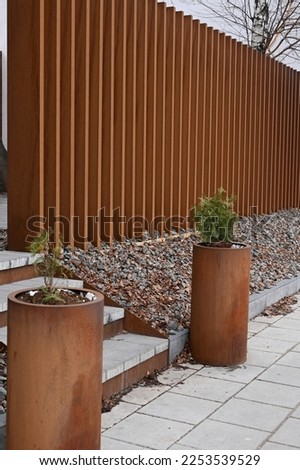 fence of rusted vertical metal elements with cylindrical flower beds Royalty-Free Stock Photo #2253539529