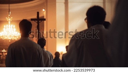 Liturgy In Church: Procession Of Ministers, Bearing Holy Cross to Altar, As Congregation Stands In Wonder. Christians Rejoice In Celebration Of Divine Mass. Hymns Praise God Royalty-Free Stock Photo #2253539973