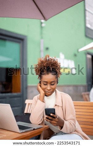 Afro woman working at her computer in bar