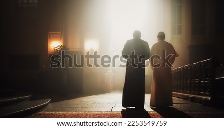 In The Church, A Priest And Pope Share A Conversation Of Faith, Reverence, Hope, Discussing Gospels and Teaching of Jesus Christ and Holy Book. Blessing Light From Tainted Window Shines on Them. Royalty-Free Stock Photo #2253549759