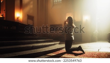 Side View: Christian Woman Getting on her Knees in Front of Altar and Starting to Pray in Church. Devoted Parishioner Seeks Guidance From Faith and Spirituality. Religious Believer in Power of God Royalty-Free Stock Photo #2253549763