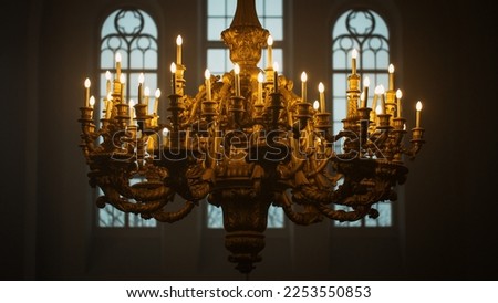 Close Up Shot of a Majestic Golden Chandelier Hanging from the ceiling of a Grand Church. An Antique Piece of Rococo Style Decorates the Cathedral and Lends Light to the Interior of the Building Royalty-Free Stock Photo #2253550853