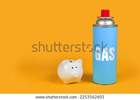 Gas cartridge bottle with piggy bank on yellow background. Concept for saving gas