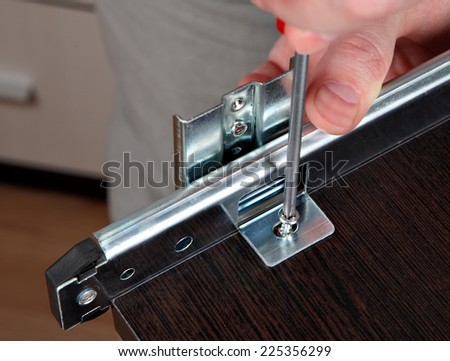 Assembling of furniture, Installing  track drawer slide rail, screwing screw manual screwdriver. Royalty-Free Stock Photo #225356299