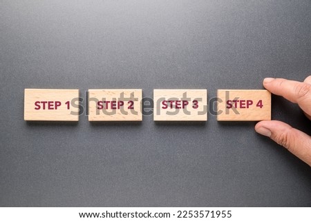 Closeup hand arrange the wood blocks of Step 1 to 4 on gray background, step process, step by step method Royalty-Free Stock Photo #2253571955