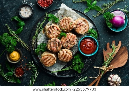 Grilled medallions wrapped in bacon. in a pan, ready to eat. On a black concrete background. Top view.