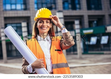 Engineer woman in safety equipment  holding plans. Building, developing, construction and architecture concept. Royalty-Free Stock Photo #2253589303