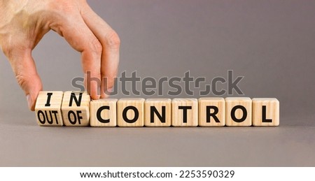 In or out of control symbol. Concept words In control and Out of control on wooden cubes. Businessman hand. Beautiful grey table grey background. Business in or out of control concept. Copy space.