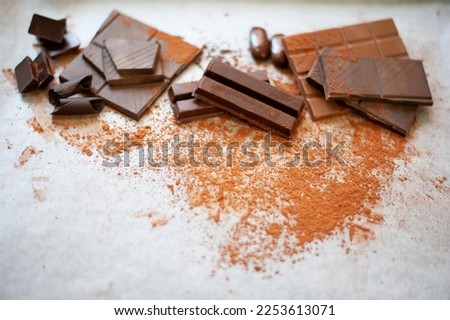 Chocolate pieces broken, dark and milk chocolate, chocolate balls on parchment paper background. Copy space.