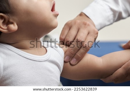unrecognizable physician's hands palpating humeral brachial pulse in infant patient Royalty-Free Stock Photo #2253622839
