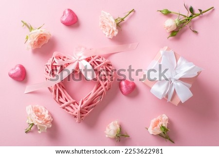 Valentine's Day background with a gift box, heart-shaped candies, a braided valentine and a bouquet of roses on a pink background. Space for copying. Flat position, top view.