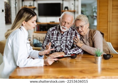 Mature couple looking at their plan of care and medications with female nurse at home.