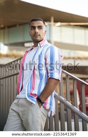 Handsome pensive  Iranian male fashion model posing for pictures standing outdoors. Stylish man relaxing on the street and looking away