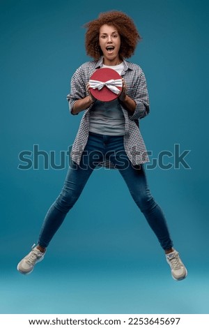 Young cute woman with a present box in hands looking excited