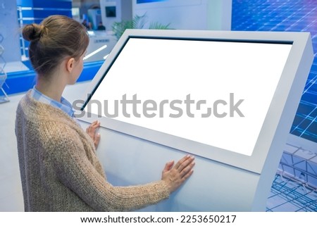 Mock up, copyspace, template, isolated, white screen, futuristic concept. Mockup: woman looking at blank white interactive touchscreen display of electronic kiosk at technology exhibition, museum Royalty-Free Stock Photo #2253650217