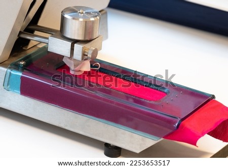 textile rubbing machine , test device that measures the friction of fabrics in the textile laboratory, taken from the left, selective focus Royalty-Free Stock Photo #2253653517