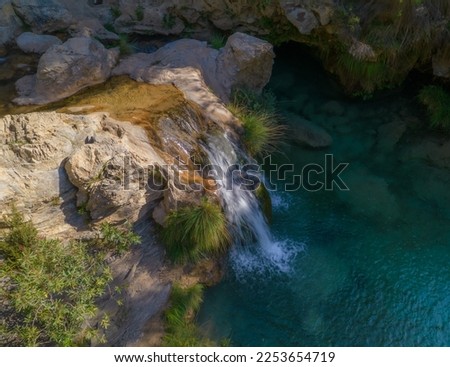 Waterfall and colorful water at sunrise. Photo long exposure silky water effect. Río Verde. Granada. Spain.