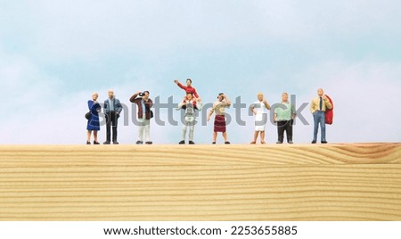 Line of Miniature People Watching Parade from Top of Wooden Box. Royalty-Free Stock Photo #2253655885