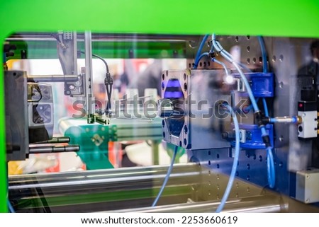 Automatic injection molding machine making disposable plastic cup at exhibition, trade show. Manufacturing, production, technology concept Royalty-Free Stock Photo #2253660619