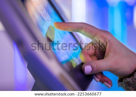 Woman hand using touchscreen display of interactive floor standing tablet kiosk at exhibition or museum - close up view. Futuristic, education, entertainment, learning, technology concept Royalty-Free Stock Photo #2253660677