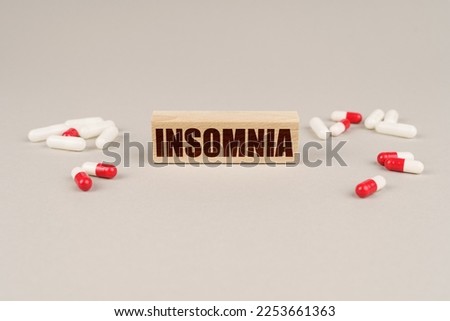 Medical concept. On a gray surface are tablets, capsules and a wooden plate with the inscription - Insomnia
