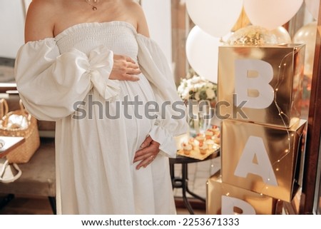 Baby shower party for friends. Pregnant mother holding her belly. Friends are waiting for a gender party. Pregnancy of a young girl in a circle of friends Royalty-Free Stock Photo #2253671333