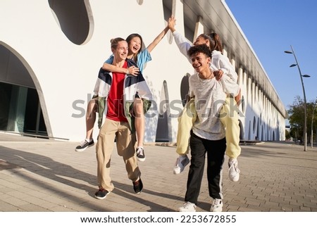 Centennials friends on vacation having piggyback and stacking hands on city street - Young people group enjoying time together laughing outdoors. High quality photo