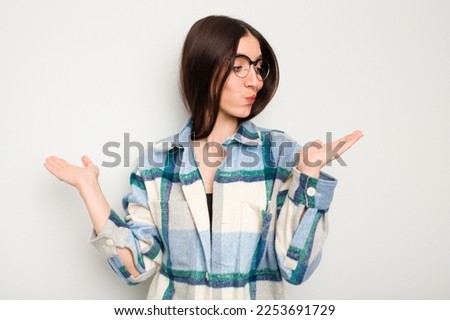 Young caucasian woman isolated on white background confused and doubtful shrugging shoulders to hold a copy space.