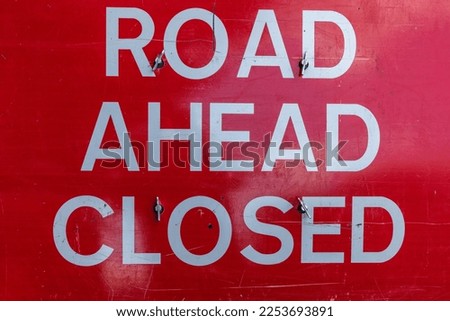 Road ahead closed warning sign, metal with white text on red