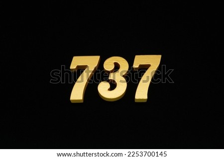 Numbers in golden yellow on a black background, numbers made of wood, then painted in yellow gold, placed on a black cloth background.