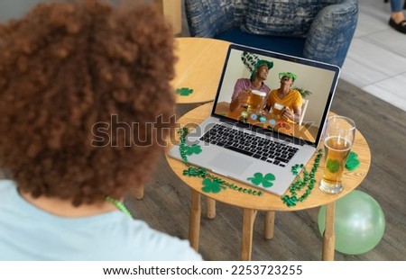 African american man having a video conference on laptop at a bar. st patricks celebration concept