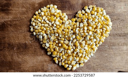 heart shaped corn kernels on brown wooden table for making popcorn