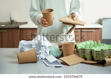 Garbage separation concept. Female hands separate paper and plastic into separate containers in the kitchen at home. Waste segregation, waste sorting, waste recycle. Royalty-Free Stock Photo #2253744679