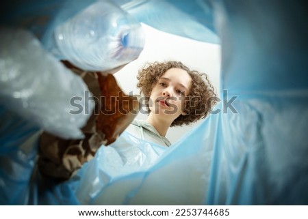 Female puts plastic bottle in trash can, view from the inside Garbage separation concept. Waste segregation, waste sorting, waste recycle. Royalty-Free Stock Photo #2253744685